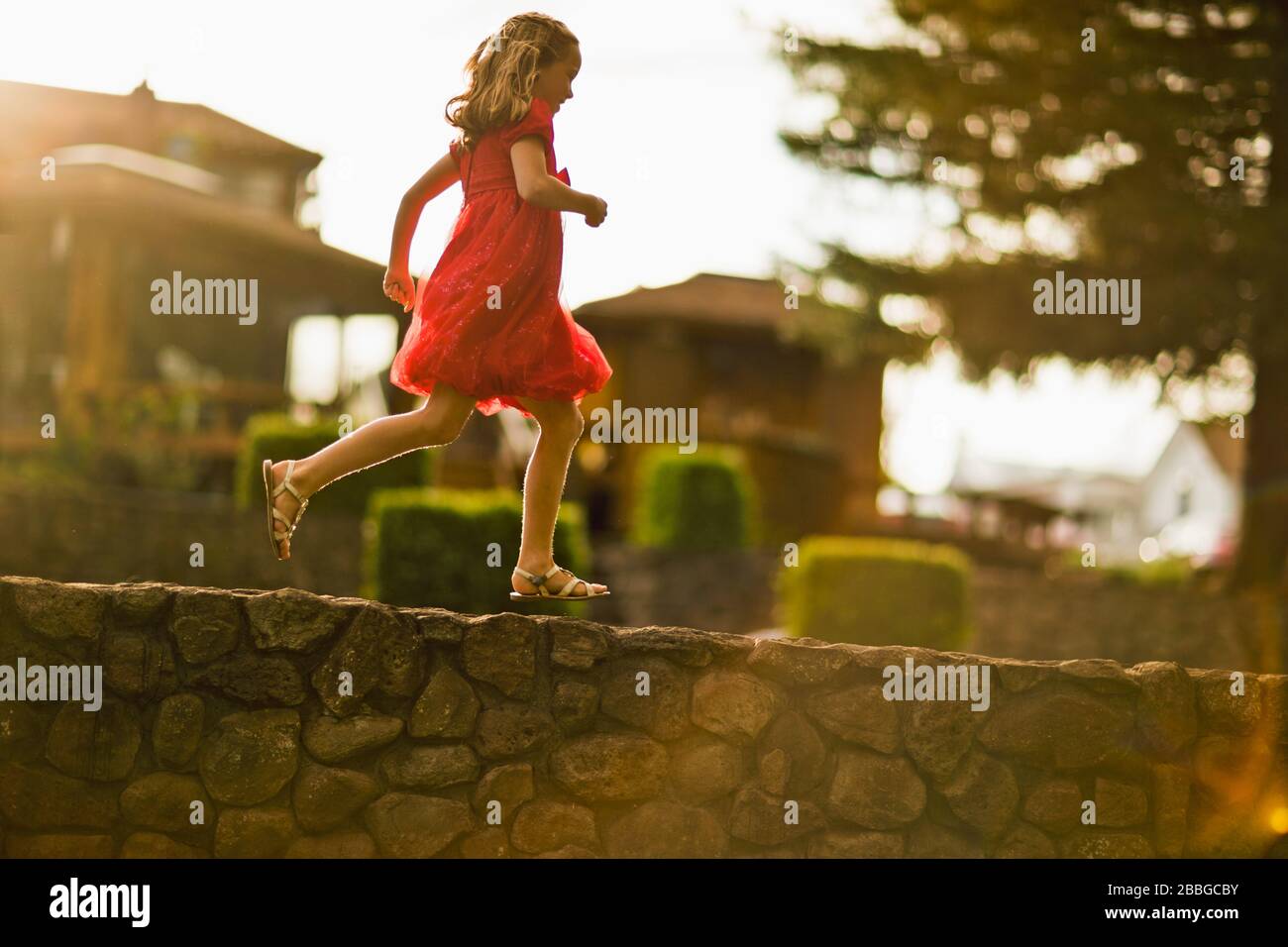 Ragazza giovane che corre lungo un muro di pietra Foto Stock