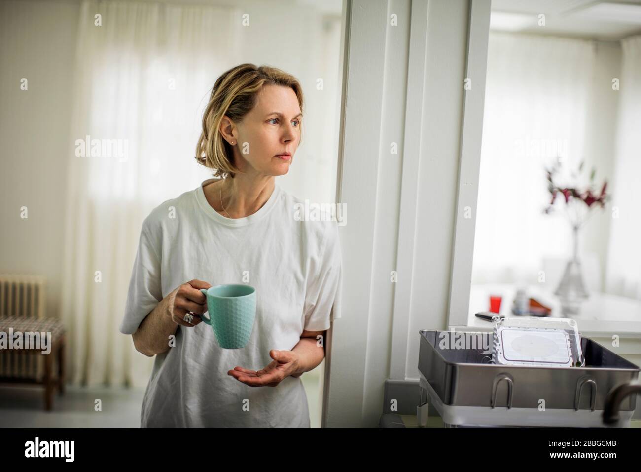 Donna matura bere caffè in cucina Foto Stock