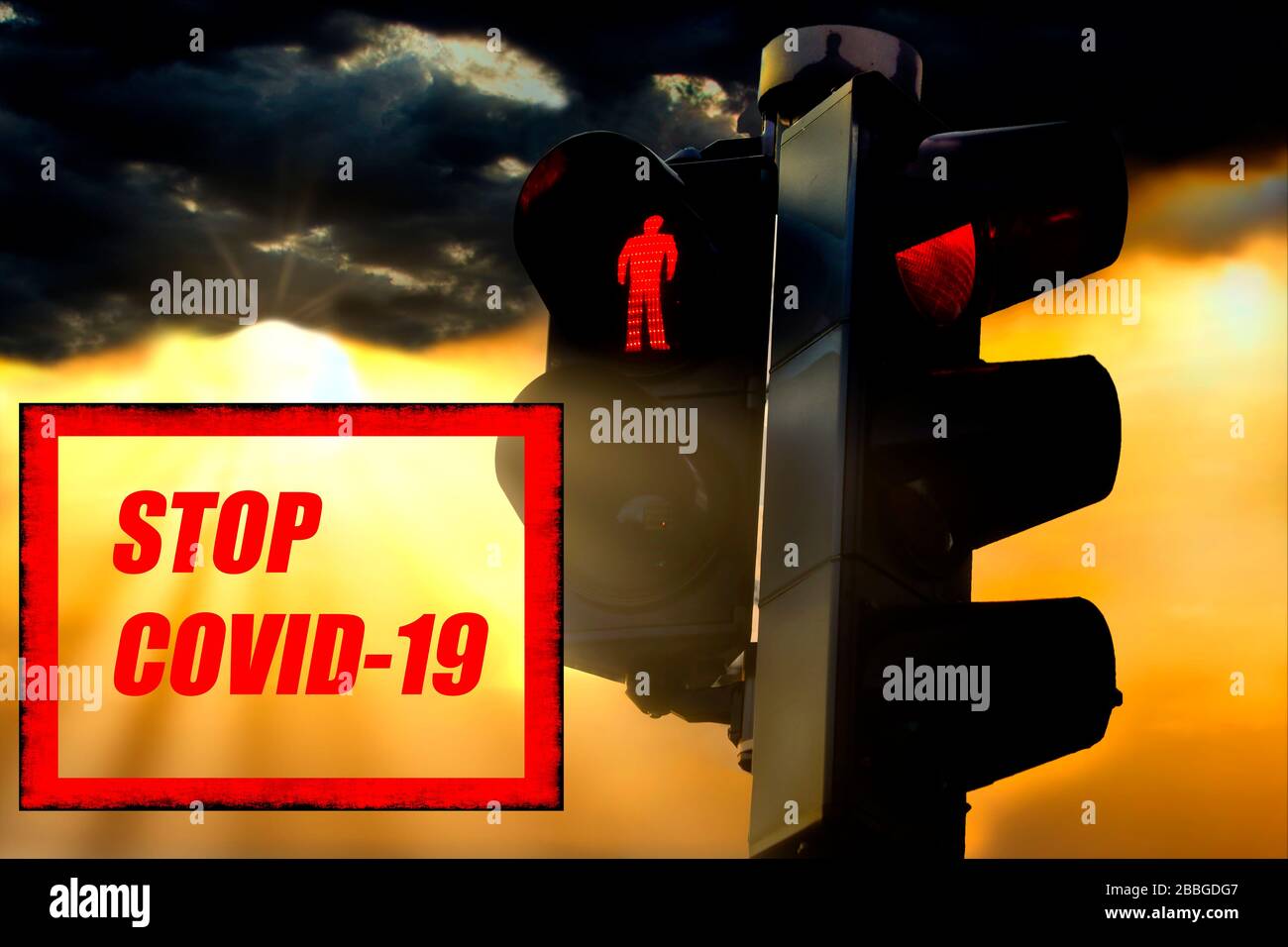 Stop Covid-19 concetto con luci di traffico rosse illuminate e sfondo cielo scuro con raggi solari. Foto Stock