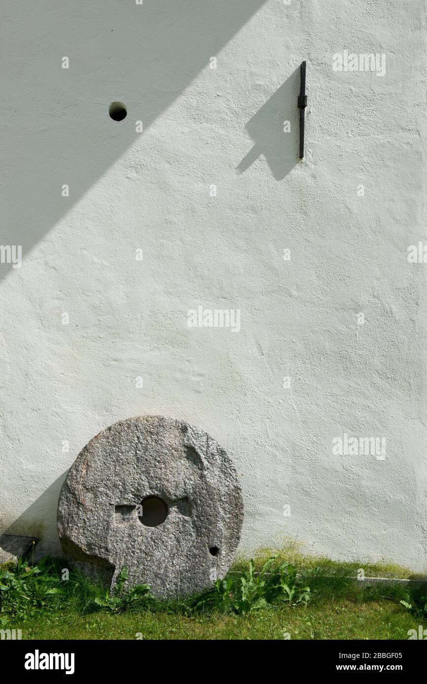 dettaglio della parete bianca della storica casa colonica austriaca con pietra di macina e chiusura in ferro Foto Stock