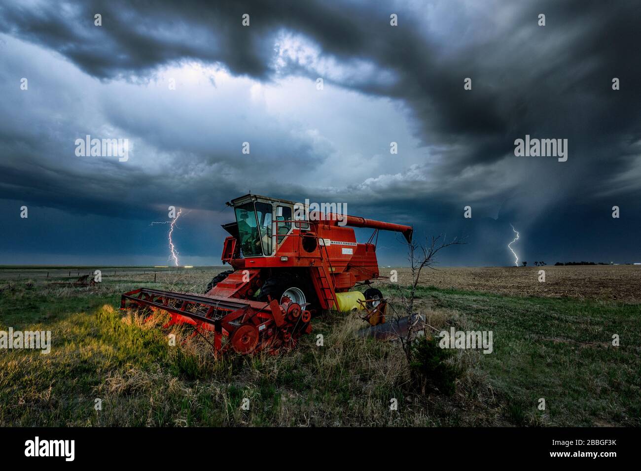 Tempesta con fulmini che si scatenano sullo sfondo con un vecchio trattore in primo piano nella rurale Kansas Stati Uniti Foto Stock