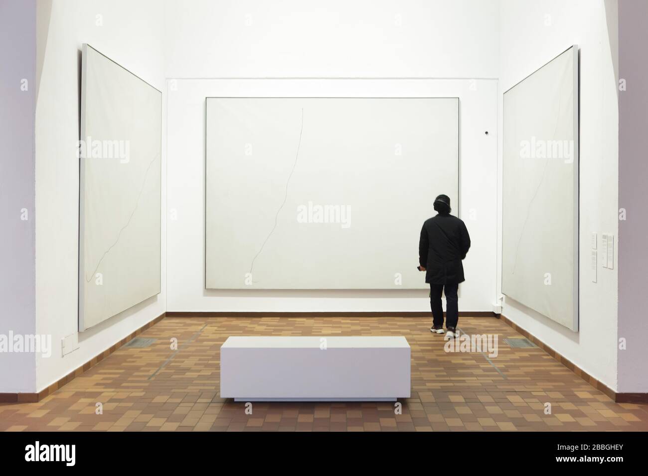 Visitatore di fronte ai dipinti del pittore modernista spagnolo Joan Miró dal titolo 'Pittura su sfondo bianco per la cella di una reclusa' (1968) esposto nella Fundació Joan Miró (Fondazione Joan Miró) a Barcellona, Catalogna, Spagna. Foto Stock