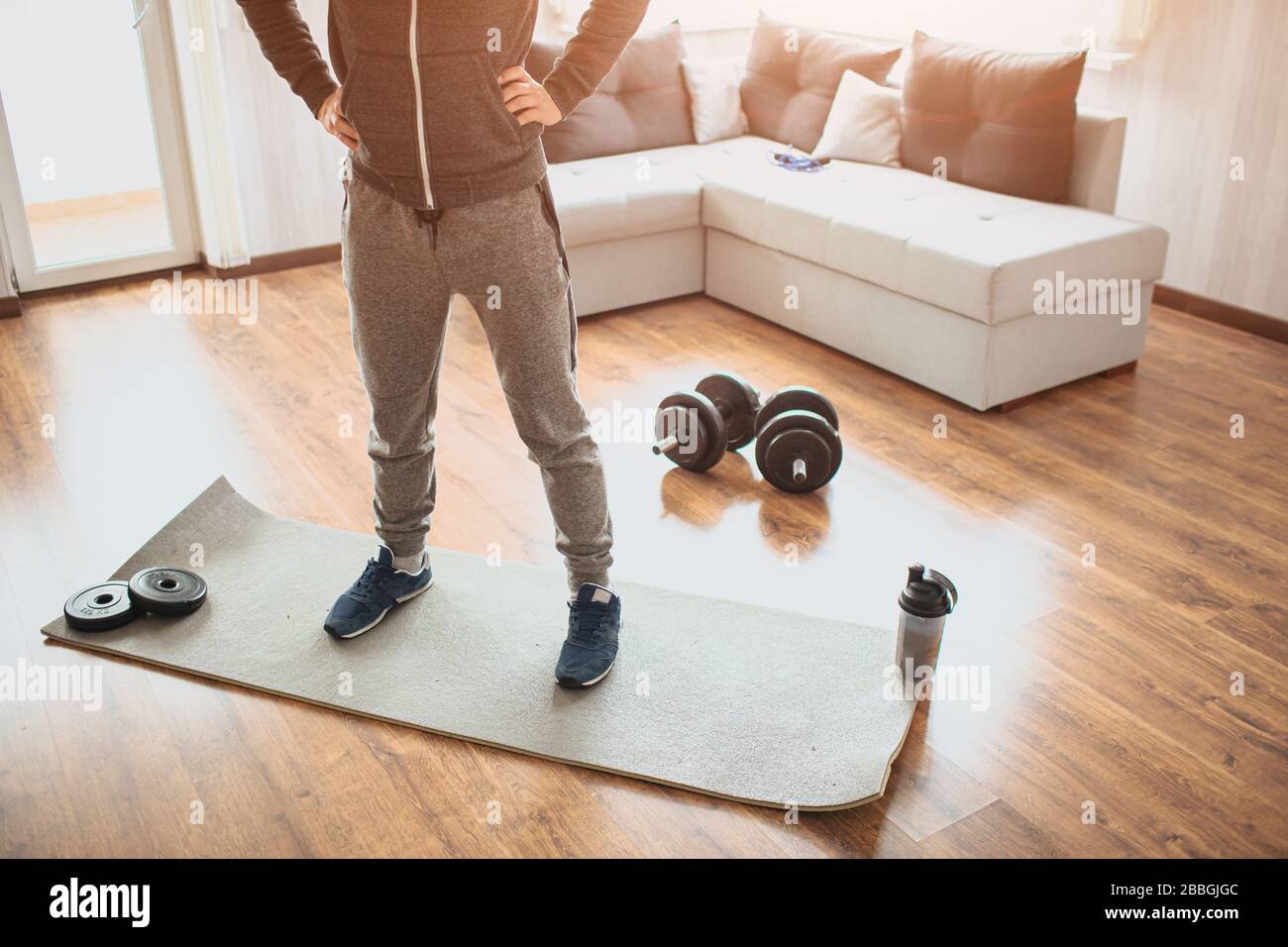 Giovane uomo ordinario va dentro per lo sport nel paese. Un normale freshman in allenamento si ferma sul tappetino e tiene le mani sui fianchi. Vista del taglio della parte bassa dell'uomo di regolare Foto Stock