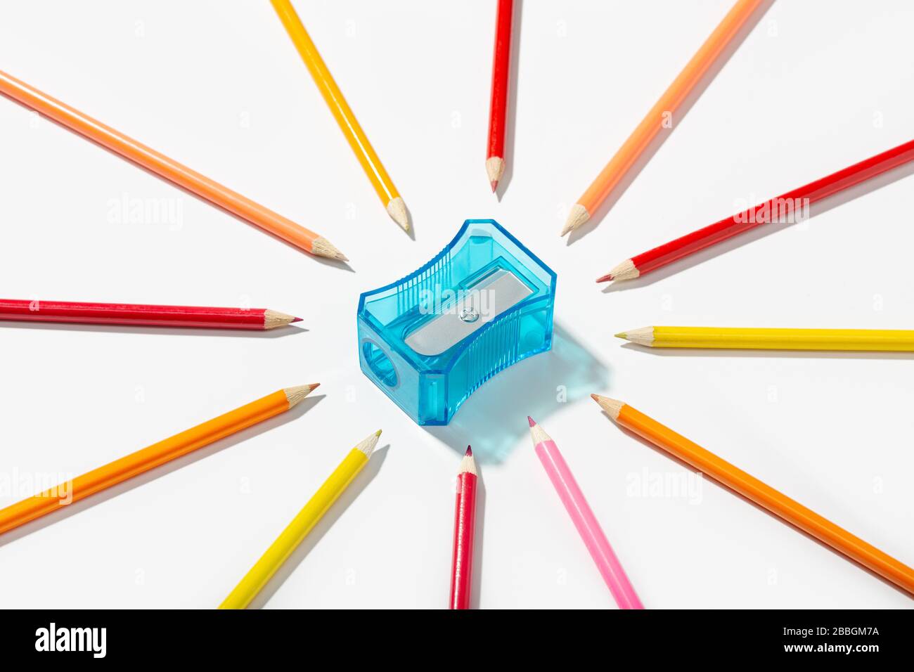 Matite multicolori e affilatrice isolate su sfondo bianco. Copiare lo spazio per il testo. Torna al concetto di scuola Foto Stock