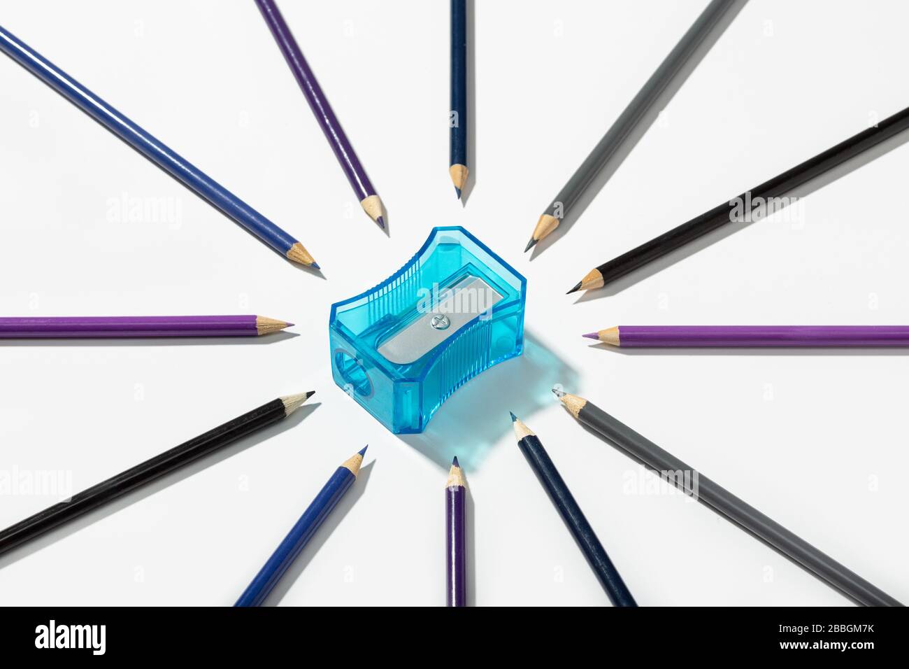 Matite multicolori e affilatrice isolate su sfondo bianco. Copiare lo spazio per il testo. Torna al concetto di scuola Foto Stock