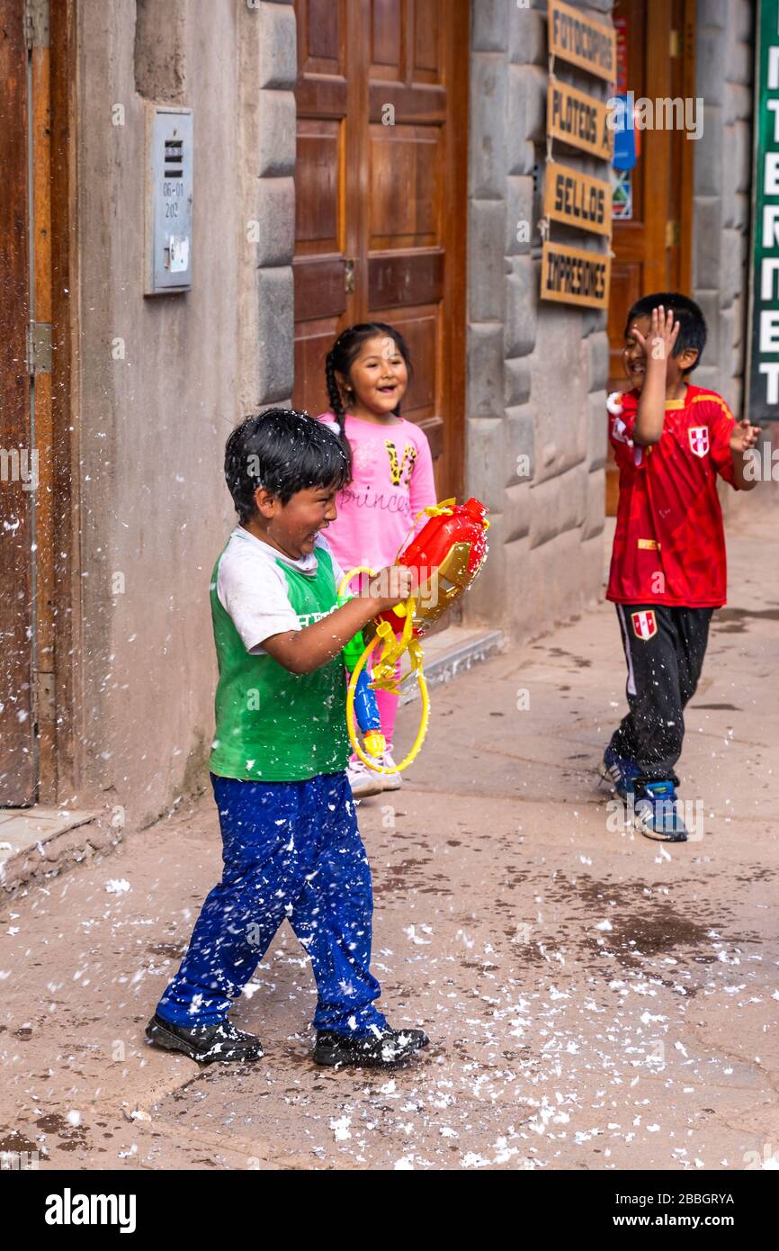 Pisac, Perù - 02.23.2020: Bambini peruviani che giocano con pistole giocattolo in schiuma per le strade di Pisac Foto Stock