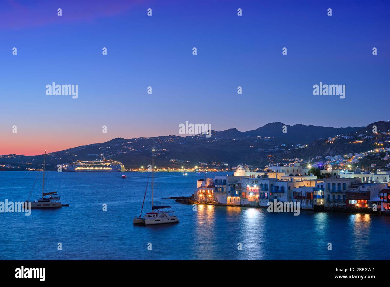 Tramonto a Mykonos, Grecia, con nave da crociera e yacht nel porto Foto Stock