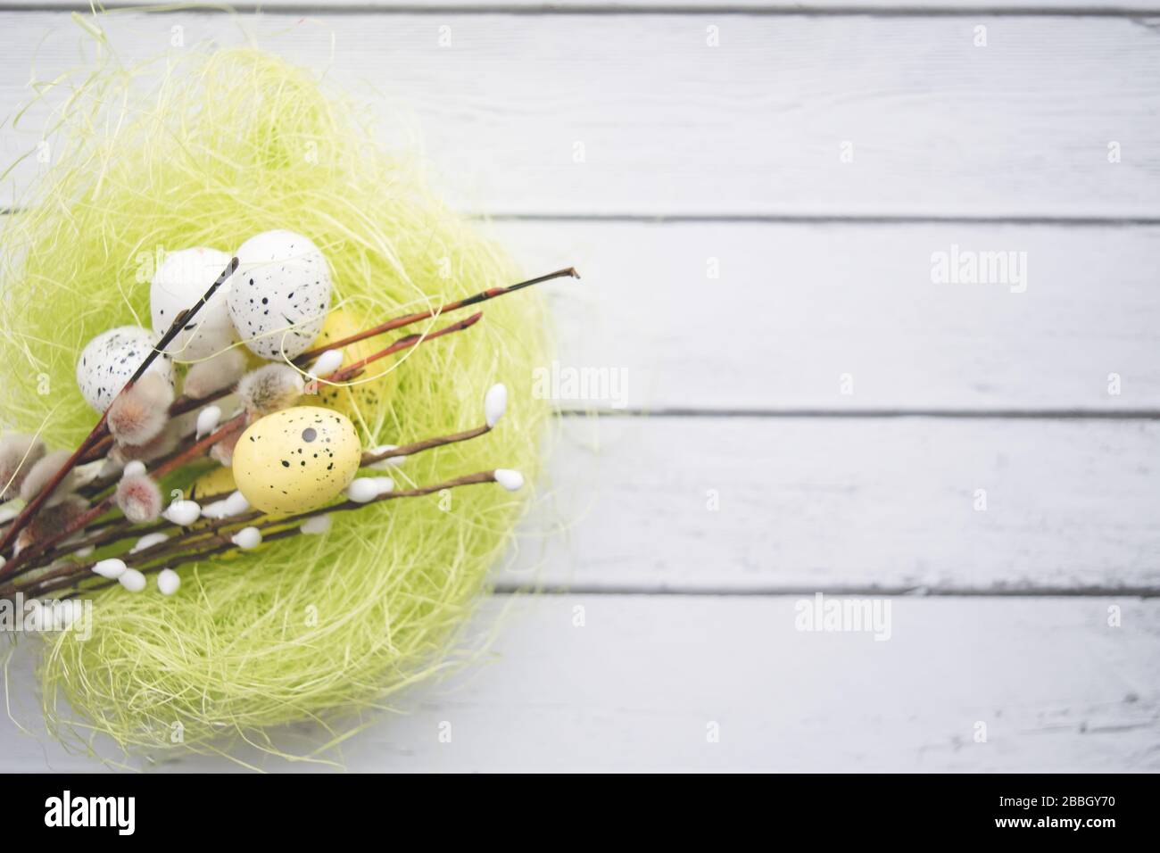 Decorazioni pasquali. Willow ramoscelli e uova decorative in nidi su sfondo di legno Foto Stock