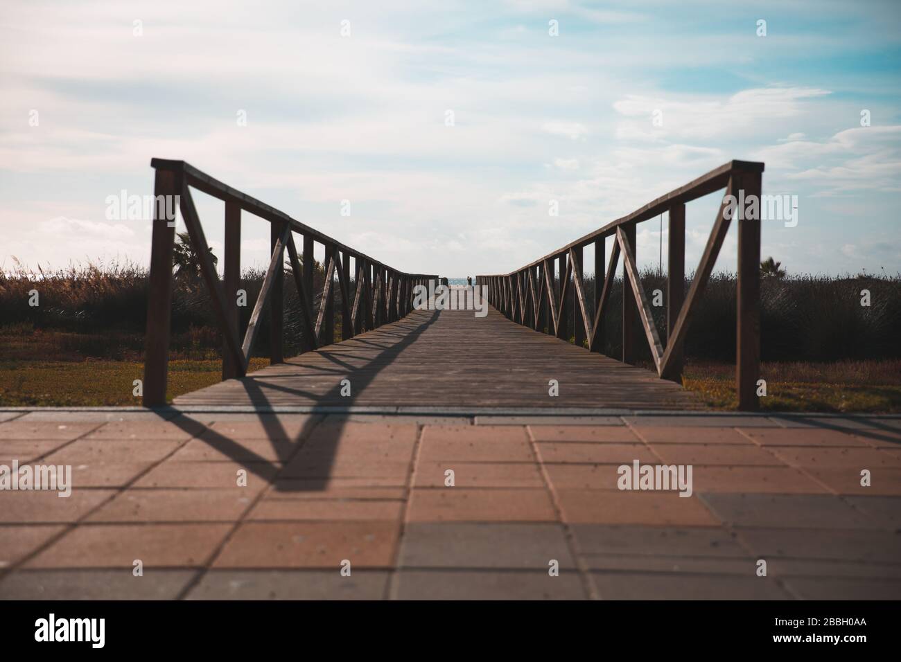 Vista prospettica di un ponte in legno costruito su pavimenti in mattoni Foto Stock