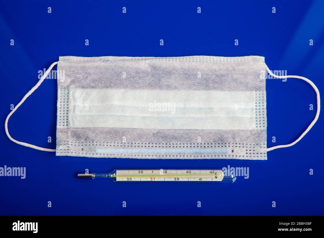 maschere mediche e termometro su sfondo blu Foto Stock