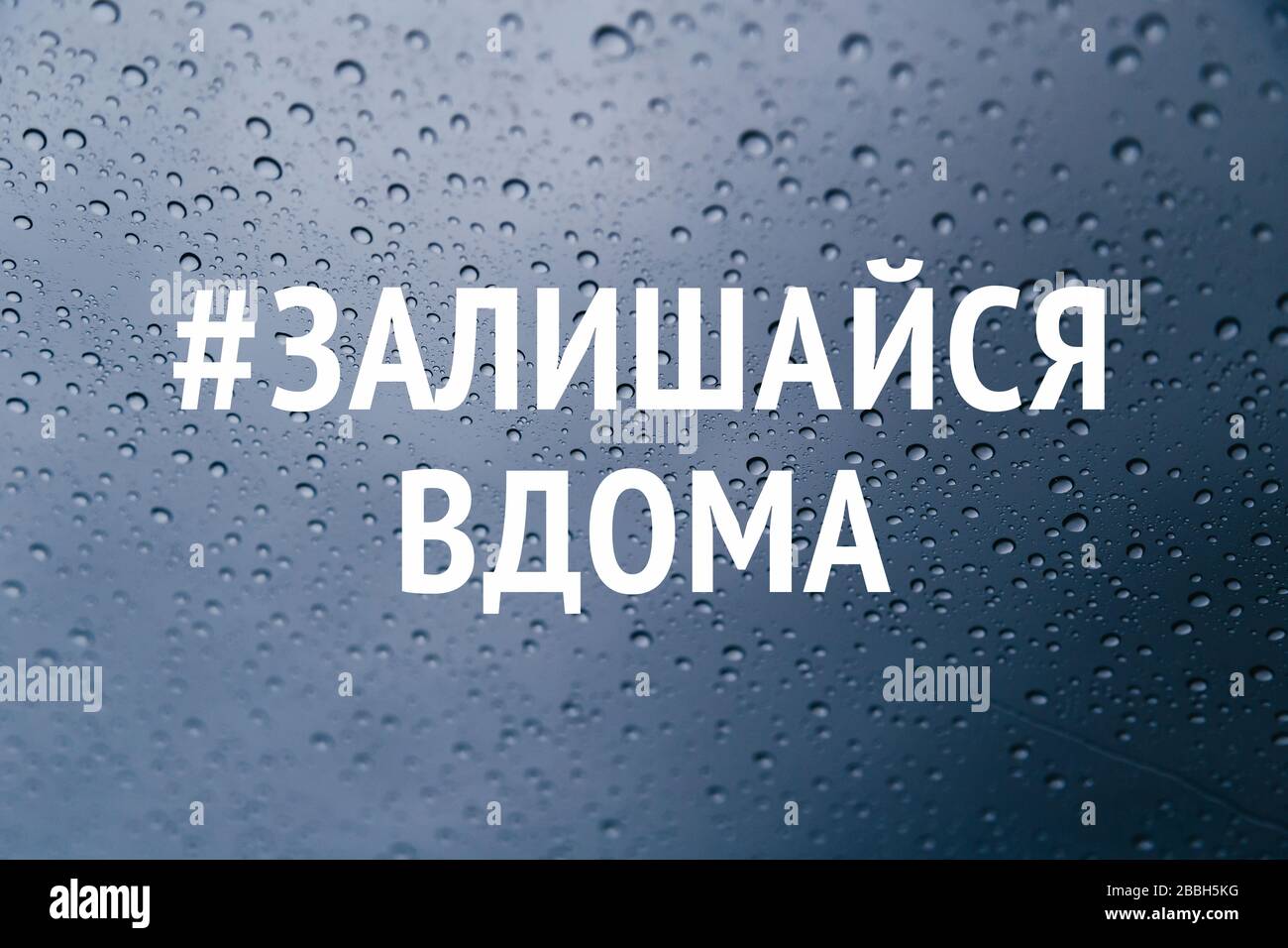 Soggiorno a casa in lingua ucraina campagna di social media per la prevenzione del coronavirus. Soggiorno a casa concetto di sicurezza. Primo piano di gocce di pioggia sul finestrino Foto Stock
