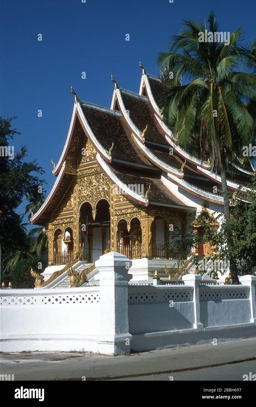 La facciata in oro e i tetti curvi sovrapposti del Tempio reale o Haw Pha Bang. Tempio buddista o wat a Luang Prabang, Laos, S.E. Asia. Costruito per ospitare il Buddha di Phra Bang, da cui Luang Prabang prende il nome. Nagas (serpenti del fiume) adornano il tetto e proteggono i gradini. La città di Luang Prabang è patrimonio dell'umanità dell'UNESCO. Foto Stock