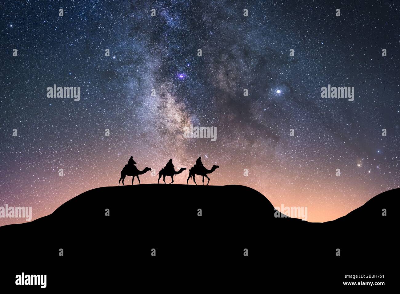 Silhouette di piloti sui loro cammelli su una duna del deserto di notte con la Via Lattea in background Foto Stock