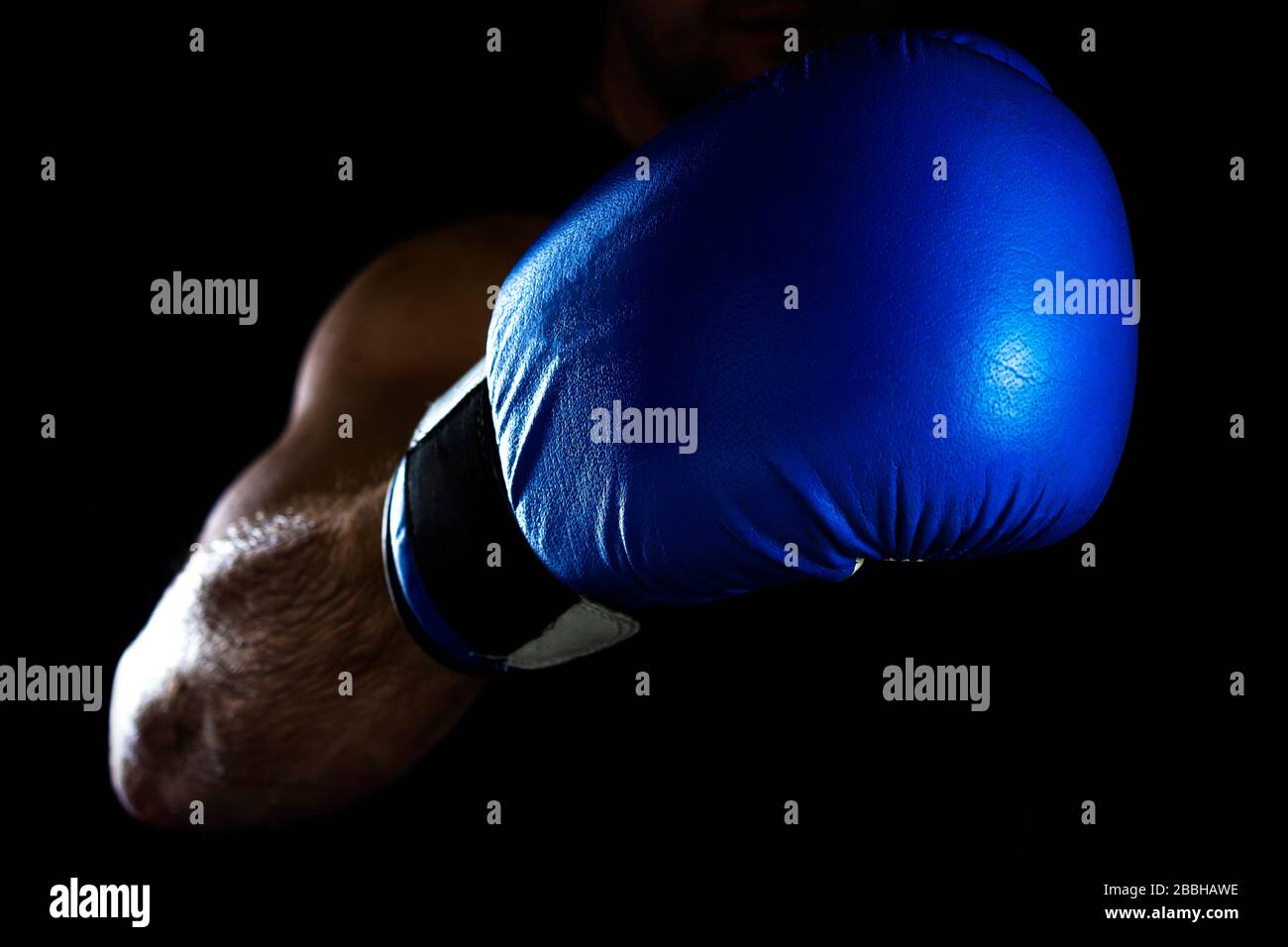 La mano degli uomini in un guanto blu da boxe su uno sfondo nero fa un pugno Foto Stock
