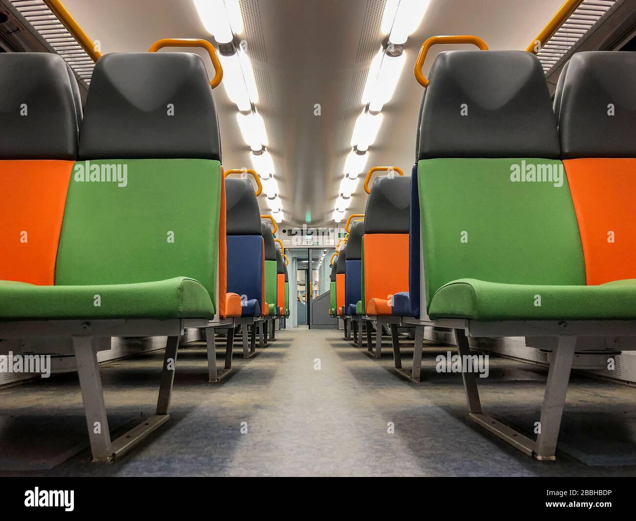 Interno di un treno moderno, prospettiva di un carrello vuoto con posti luminosi multicolore Foto Stock