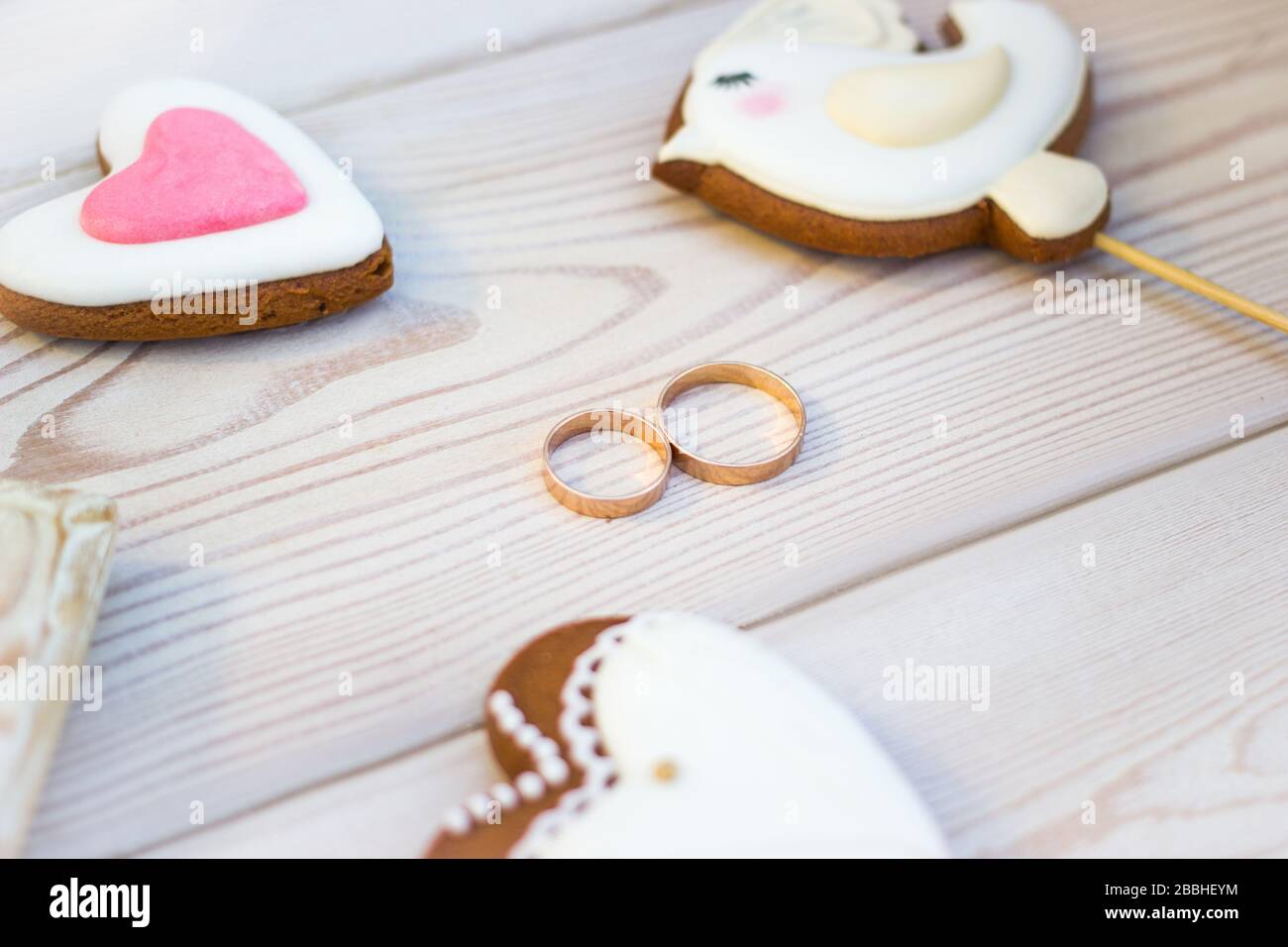 Vista ravvicinata sui biscotti a forma di cuore bisquits su bastone e anelli da sposa. Foto Stock