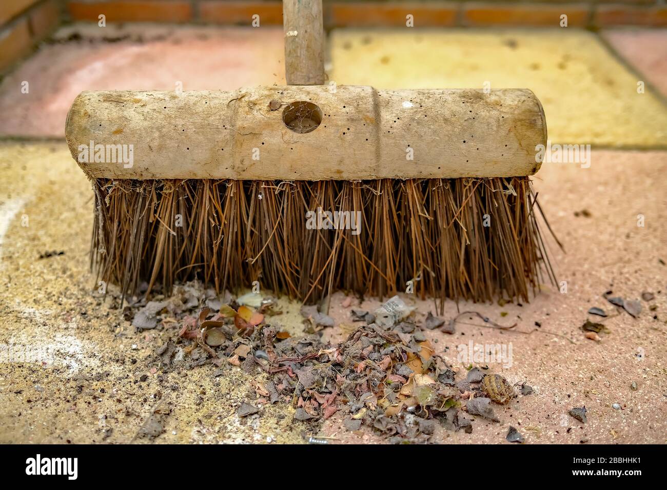 Primo piano di sporcizia e detriti sul pavimento con una testa di scopa dietro Foto Stock