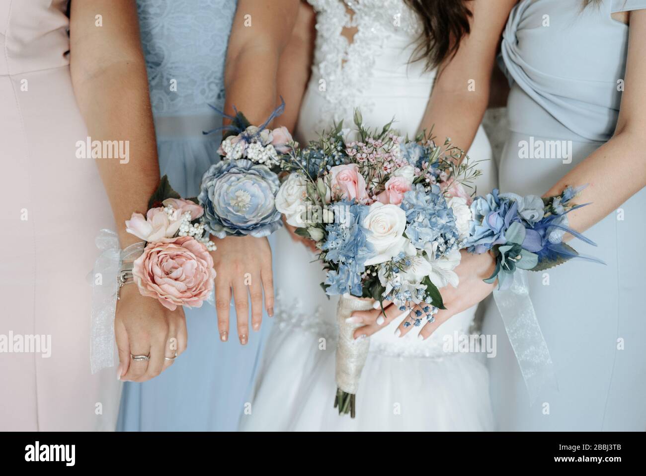 Sposa e bridesmaids mano con bei fiori. I bridesmaids hanno controllo sui bouquet Foto Stock