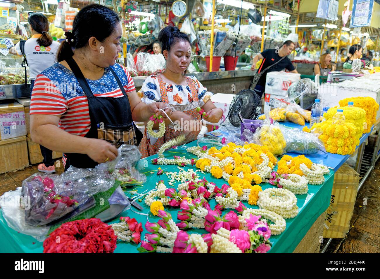 Donne che fanno fiori di margherite accordi per offrands in Pak Khlong Talat mercato dei fiori, Bangkok. 20 gennaio 2020 Foto Stock