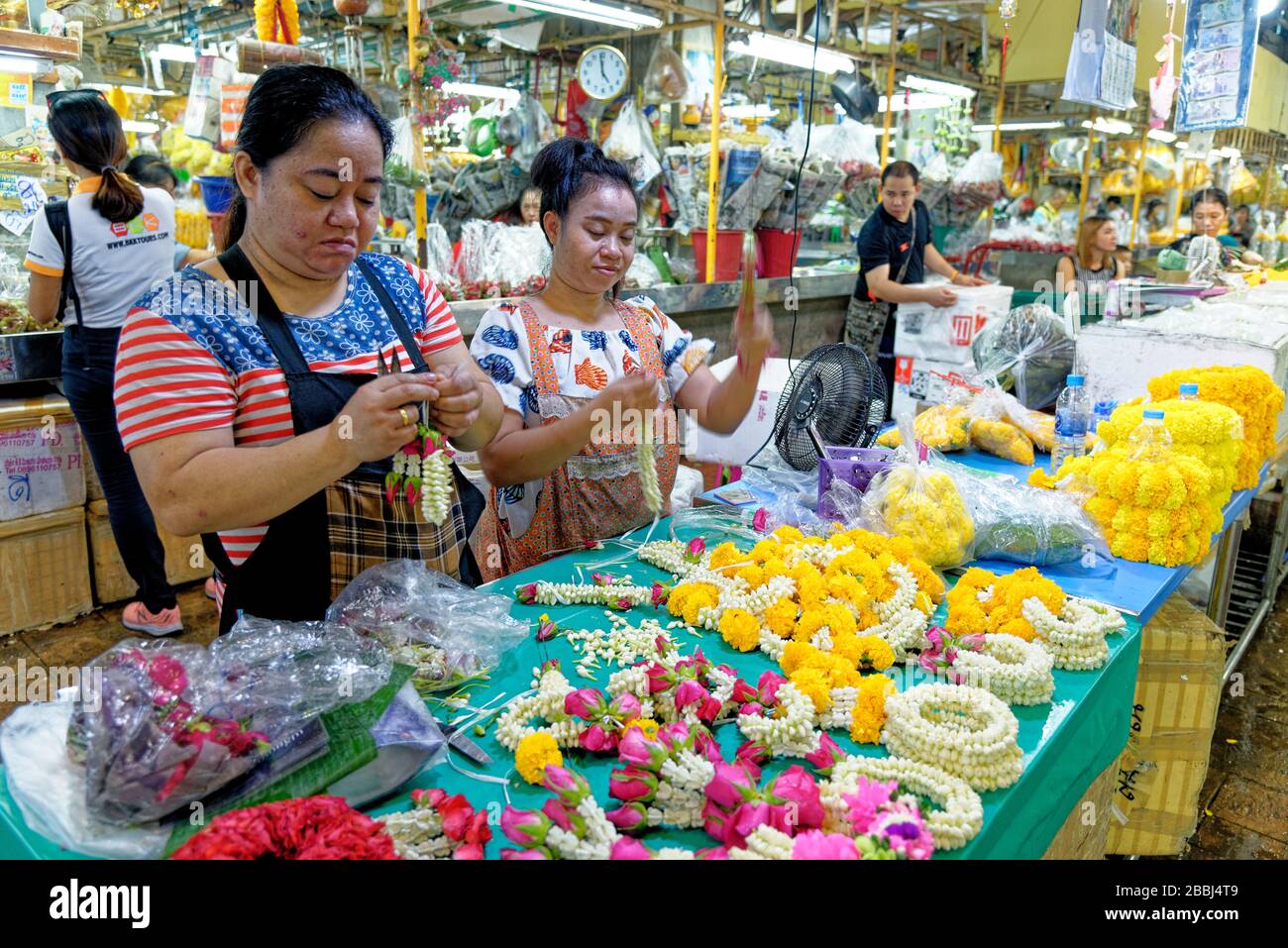 Donne che fanno fiori di margherite accordi per offrands in Pak Khlong Talat mercato dei fiori, Bangkok. 20 gennaio 2020 Foto Stock