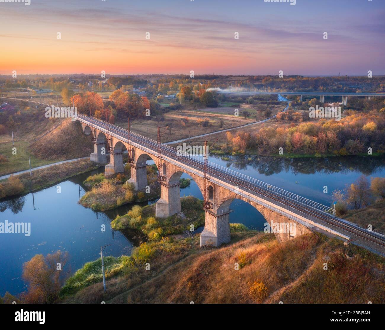 Vista aerea del ponte ferroviario e del fiume al tramonto in autunno Foto Stock