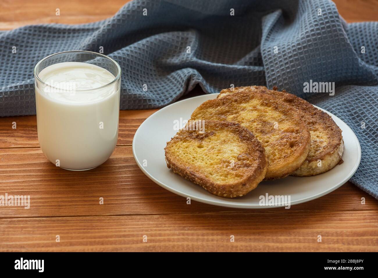 Toast alla francese - Przenice - fette di pane impregnate di uova sbattute e latte e fritte, con un bicchiere di yogurt su un tavolo di legno. Pane eggy, pane tostato Bombay Foto Stock