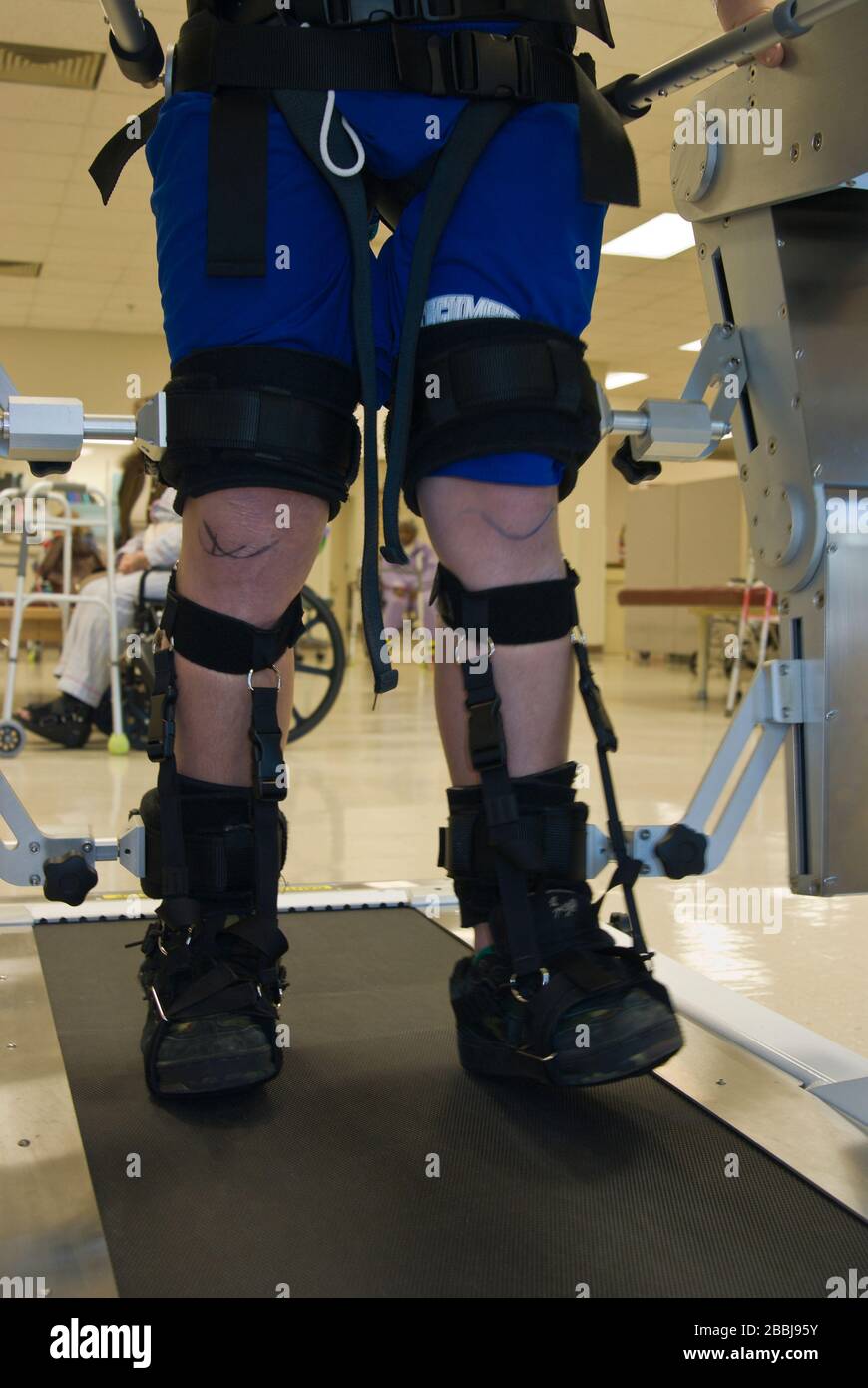 Vista parziale di un uomo in terapia fisica su una macchina che aiuta le gambe paralizzate a camminare Foto Stock