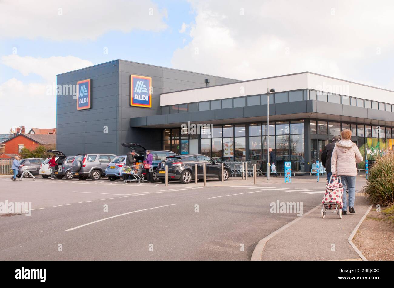 Lady con carrello per lo shopping al negozio di prezzi di Aldi presso Poulton le Fylde Lancashire Inghilterra Regno Unito Foto Stock