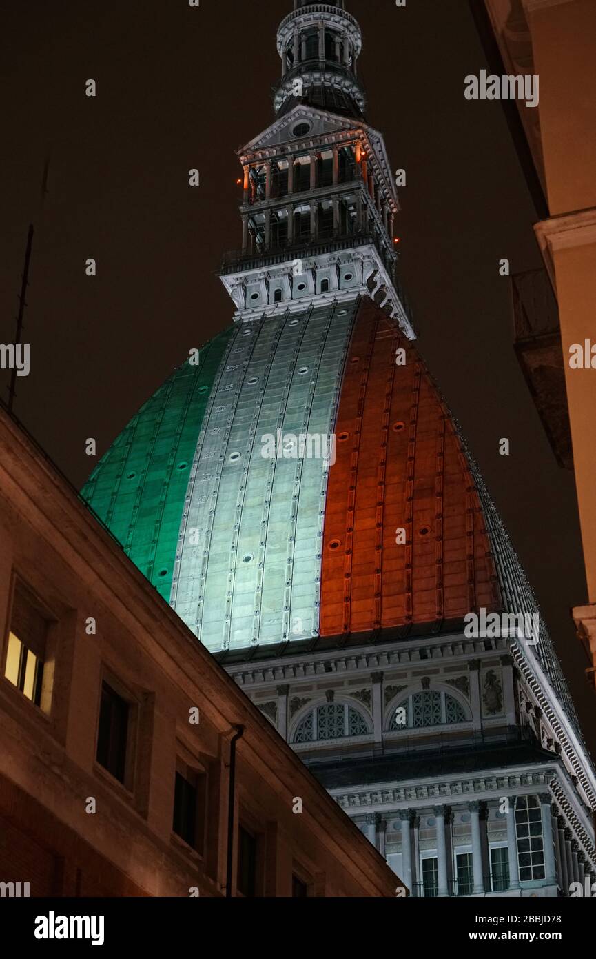 La Mole Antonelliana è illuminata dalla bandiera italiana per ricordare le numerose vittime della pandemia di coronavirus. TORINO, ITALIA - MARZO 2020 Foto Stock
