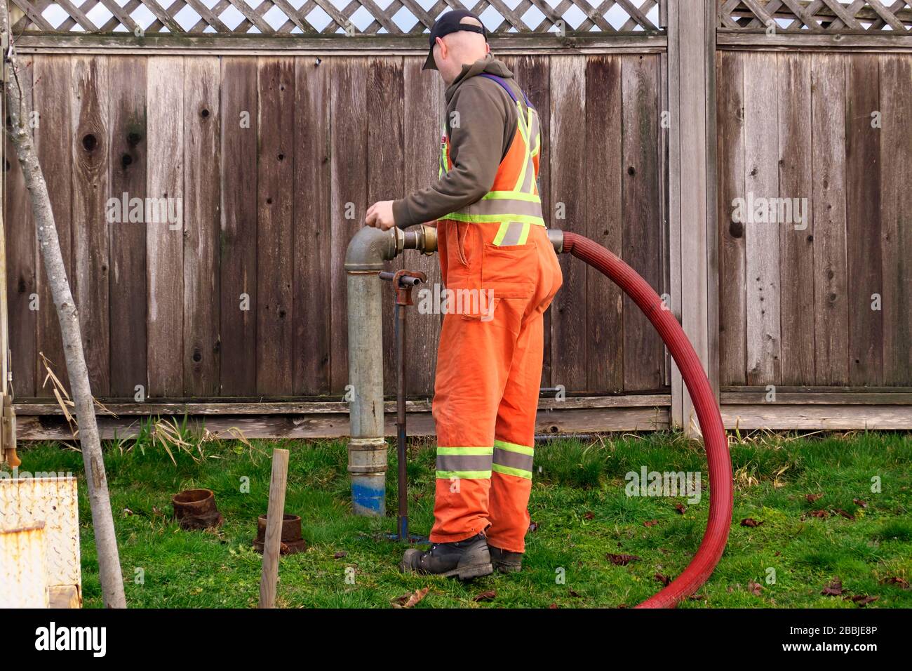 Un operaio comunale in tute arancioni che fanno manutenzione in Pitt Meadows, B. C., Canada. Foto di scorta. Foto Stock