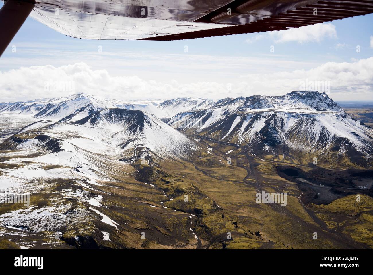 Vista aerea delle montagne islandesi dall'ala dell'aereo pov Foto Stock