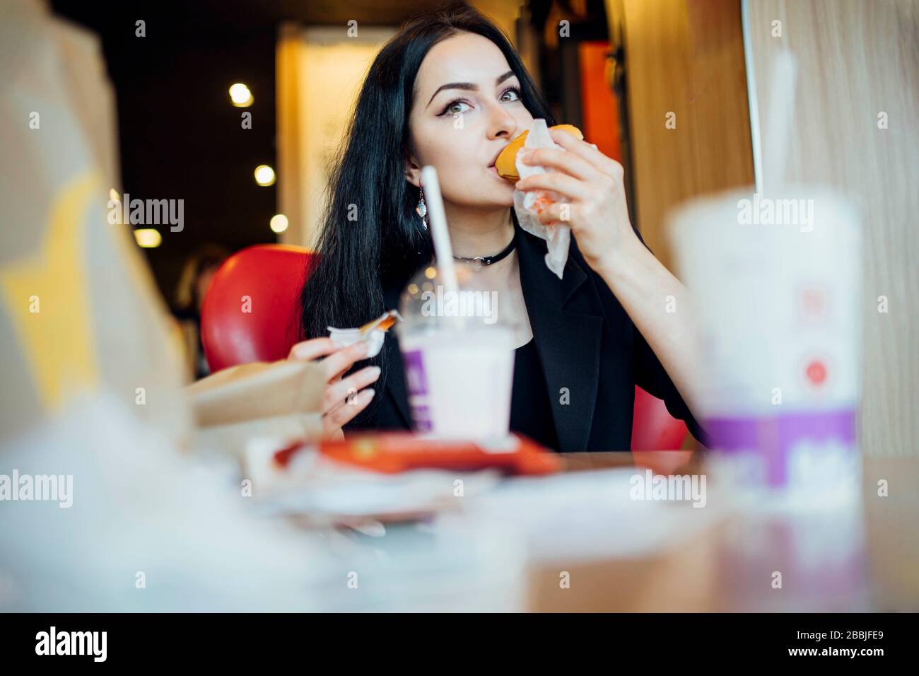 Donna che mangia un hamburger in un bar Foto Stock