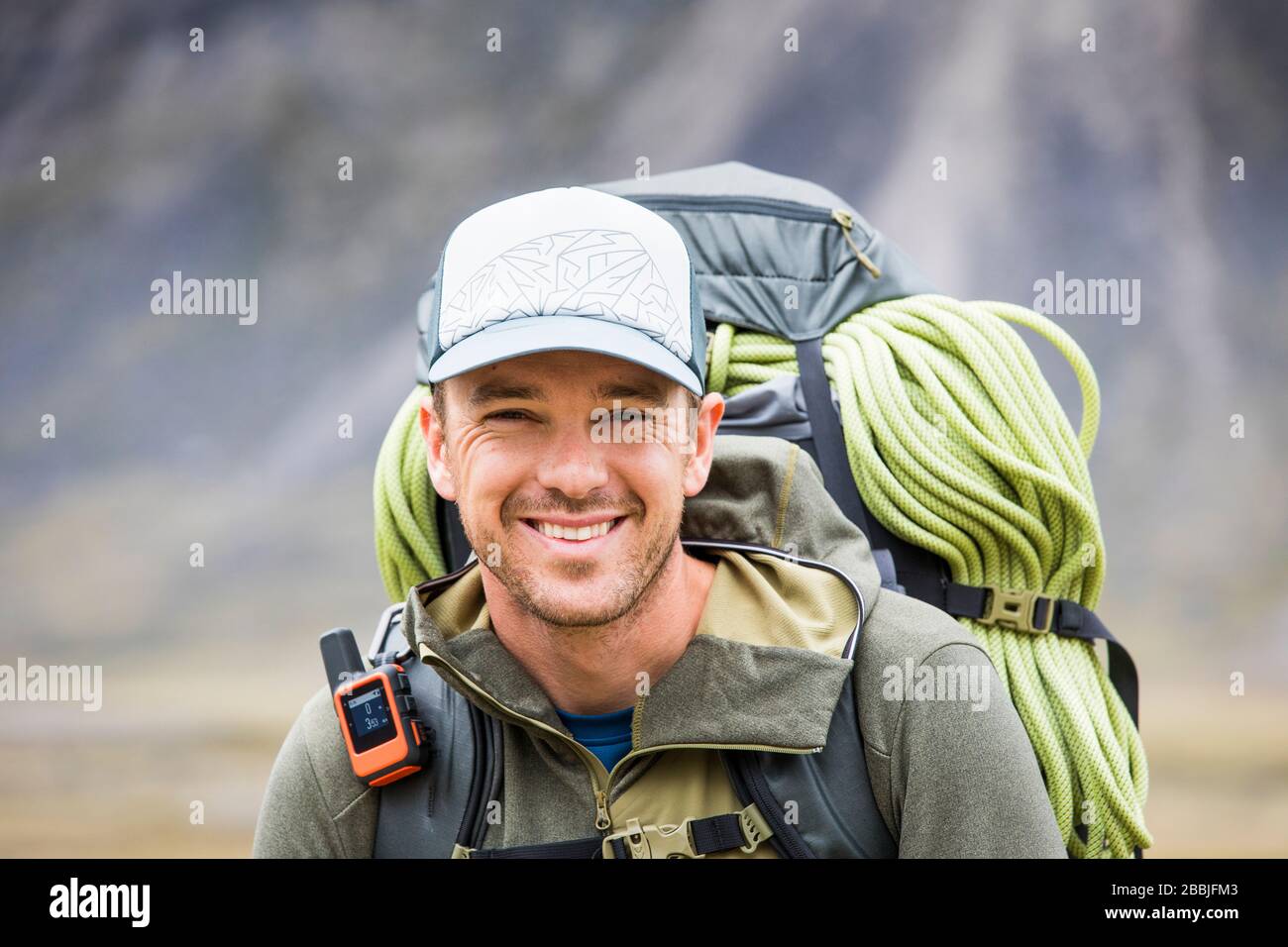 Ritratto di scalatore che indossa zaino, corda e strumento di comunicazione GPS Foto Stock