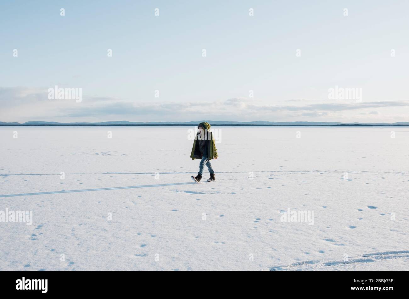 Ragazzo che cammina attraverso un lago ghiacciato solo in Svezia Foto Stock