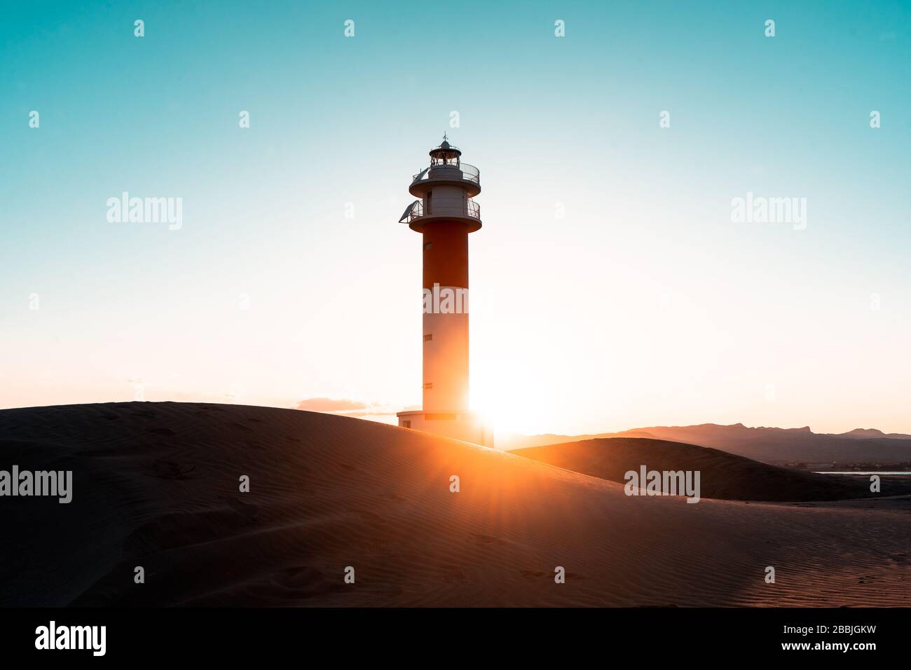 lontano faro acqua cielo tramonto Foto Stock