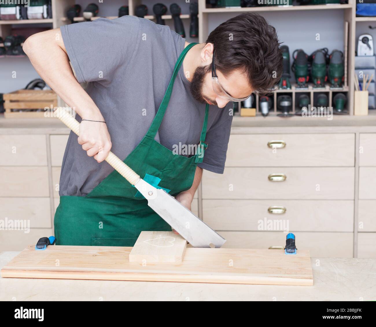 Falegname. Un giovane portacolpo in un'officina di carpenteria sega giapponese. Officina. Foto Stock