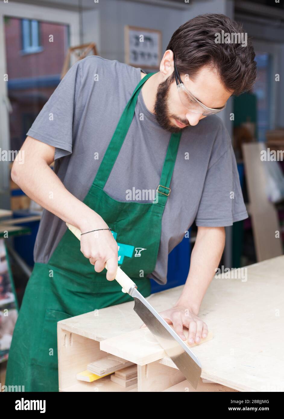 Un falegname. Un giovane hippper bearded in un'officina di Falegnameria sega un giapponese scosceso Foto Stock
