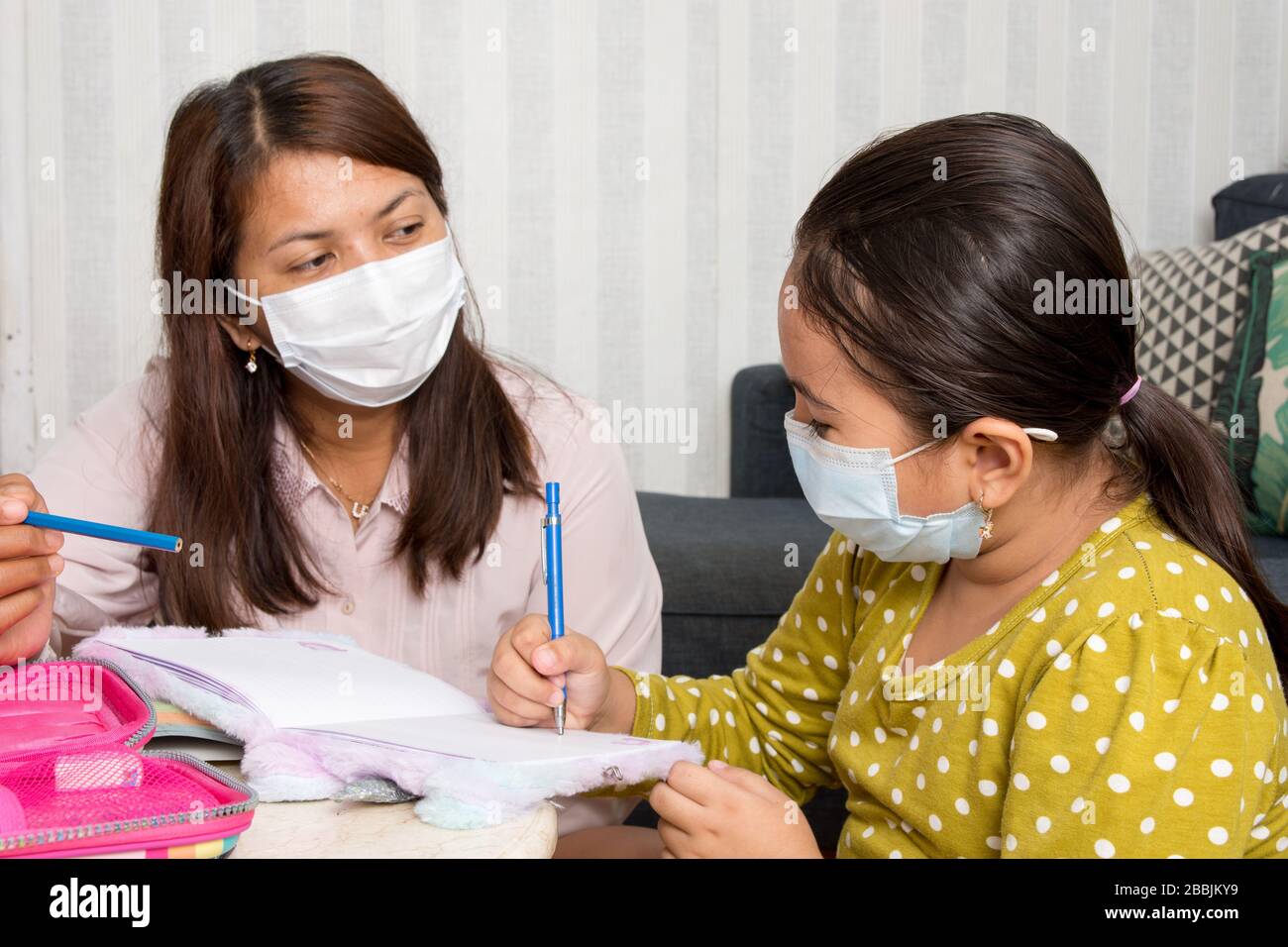 Home scuola idea immagine con madre e figlia studiare mentre indossando maschere viso a causa della minaccia attuale del virus corona - current Health care / Foto Stock