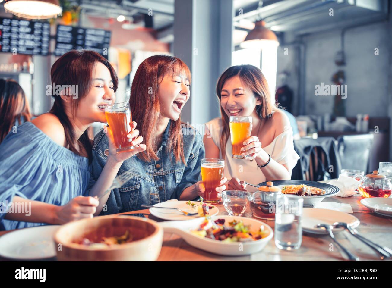 giovane donna felice seduto nel ristorante e godere la cena e la birra Foto Stock