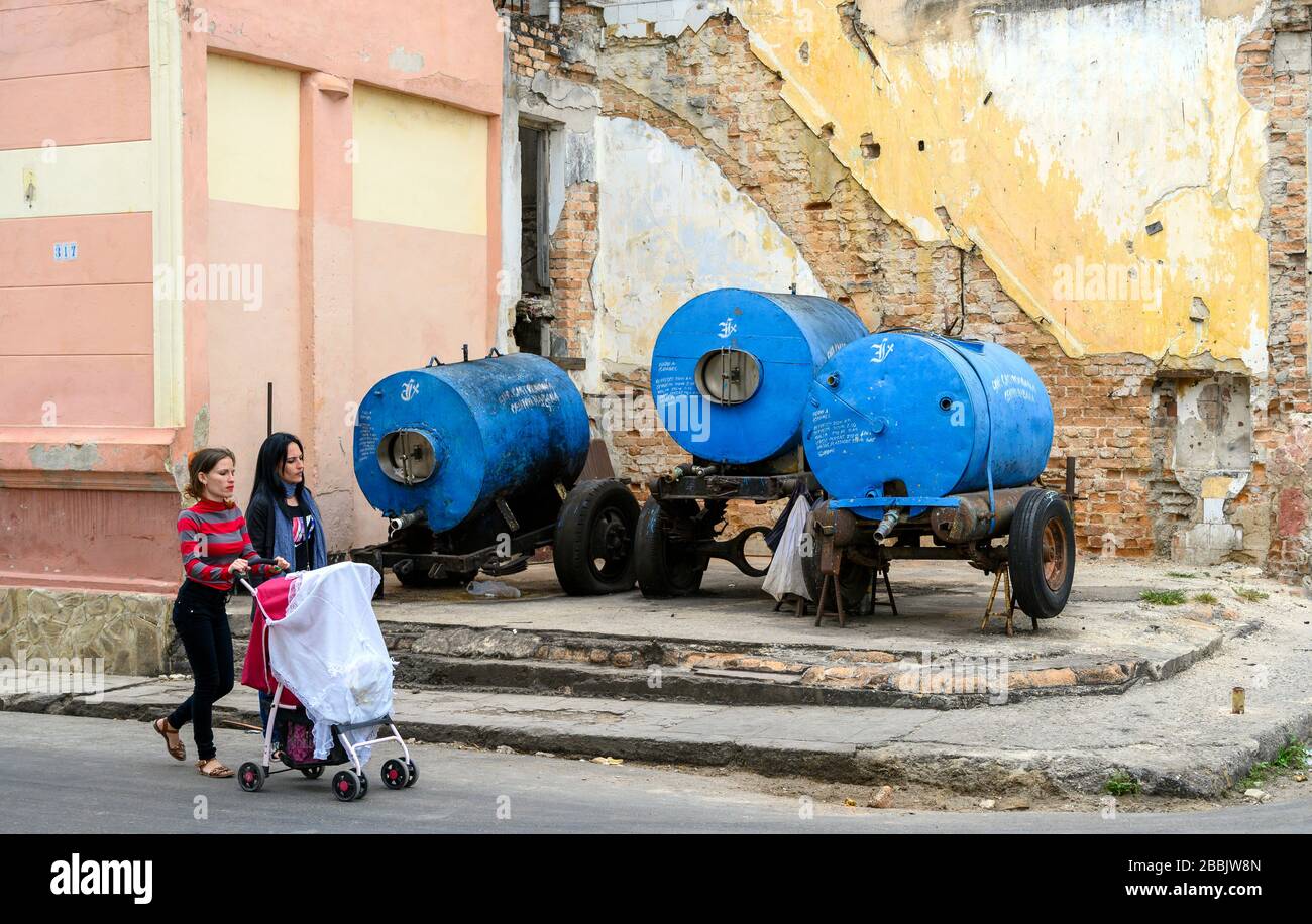 Donne con stroller camminare oltre carri armati, l'Avana, Cuba Foto Stock