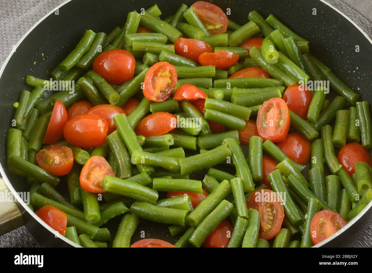 Fagioli verdi e pomodori d'uva saltati con olio d'oliva in padella Foto Stock