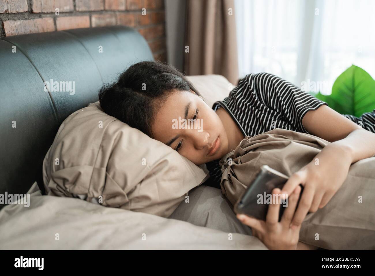 pressione pari. giovane ragazza asiatica si sente depressare mentre usa il suo telefono cellulare a casa Foto Stock