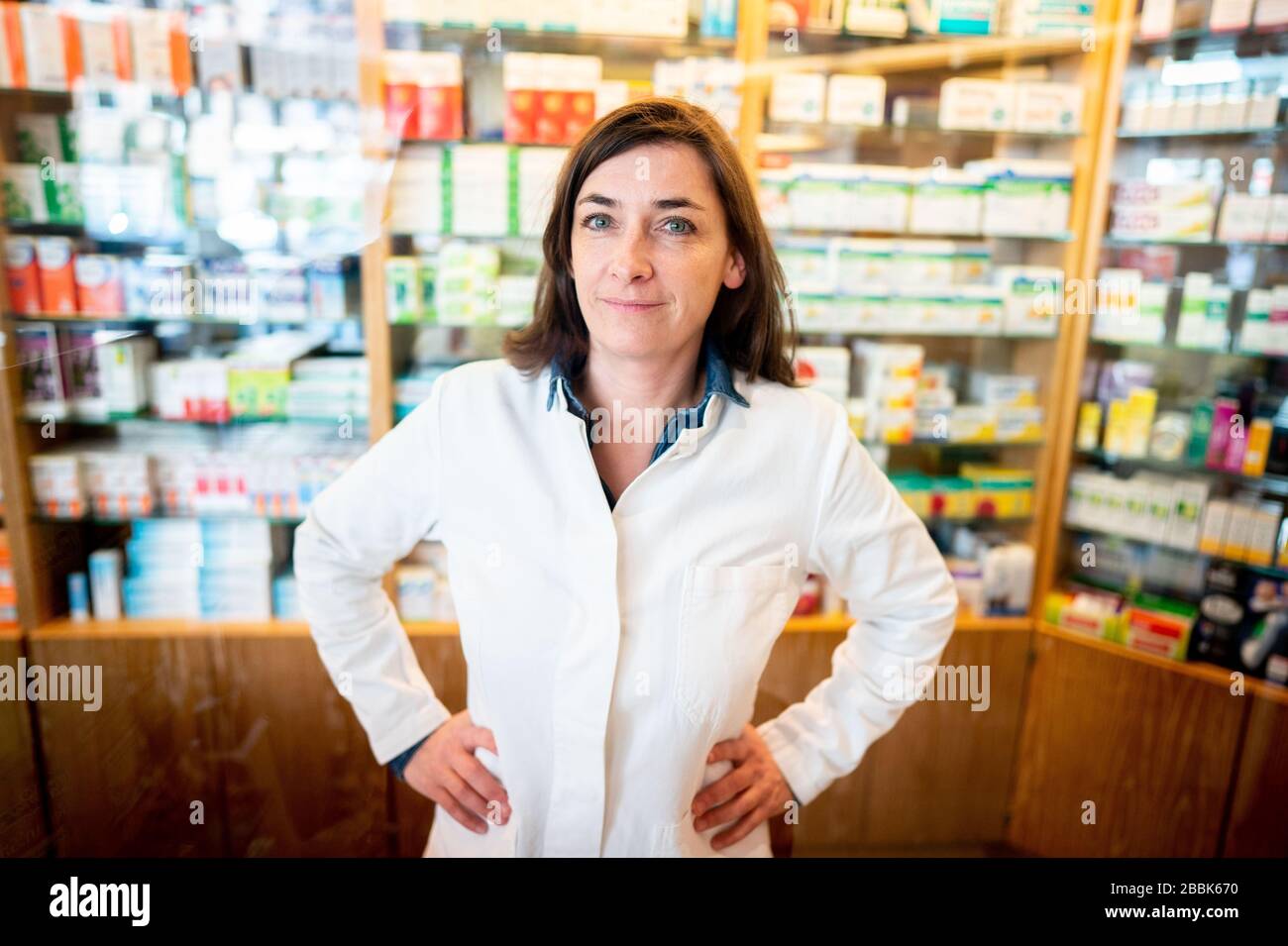 26 marzo 2020, Berlino: Anna Frerech, farmacista a Berlino-Friedenau, guarda la macchina fotografica del fotografo. Non ha paura di essere infettata dal virus corona. La sua farmacia era già dotata di uno 'scudo' all'inizio della crisi. Tuttavia, il carico di lavoro per lei e per i suoi colleghi è quasi raddoppiato. Solo dalle restrizioni iniziali del 23.03.2020 è diventato un po' più silenzioso. Per rallentare la diffusione del coronavirus, il governo federale ha ulteriormente limitato notevolmente la vita pubblica. (A 'Photo series on silent heroes of the corona Crisis in Berlin'/ part Foto Stock