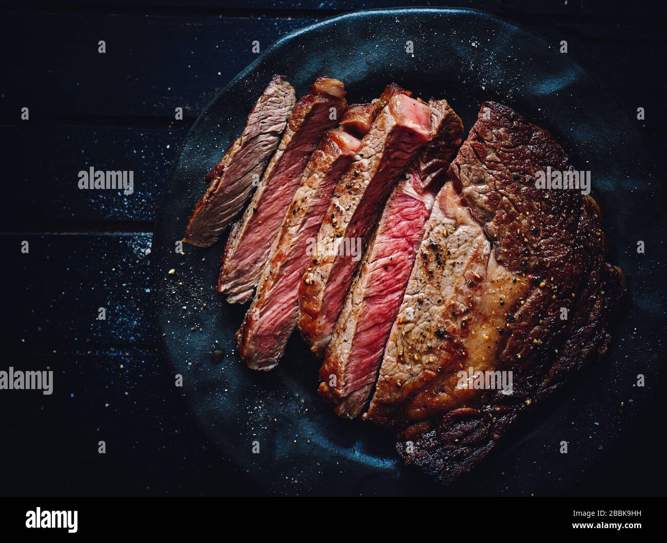 Deliziosa bistecca di Angus, di medie dimensioni, fatta in casa, di colore nero, con vista dall'alto su un piatto Foto Stock