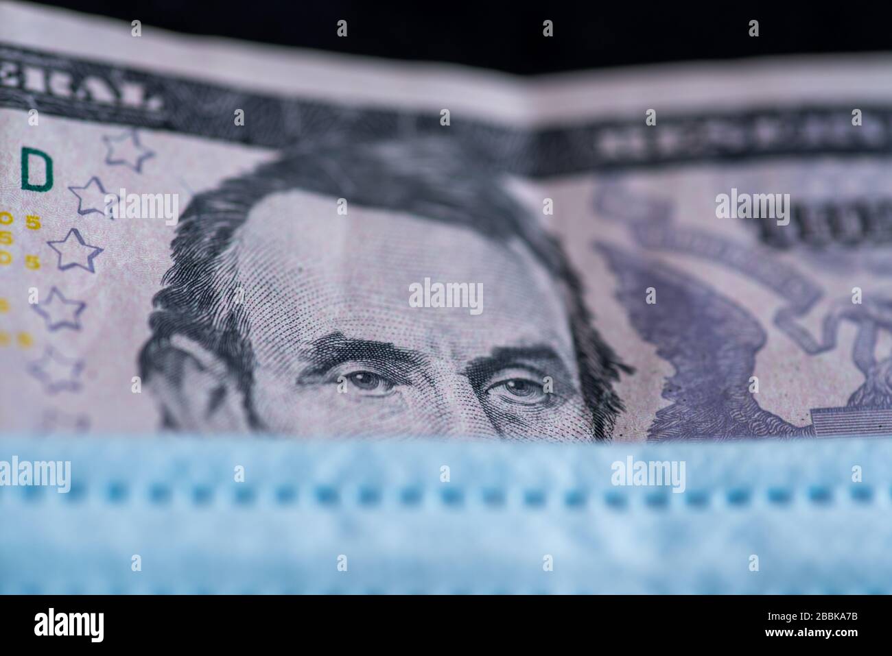 Note bancarie sotto maschera facciale - simbolo della pandemia globale del virus corona sull'economia Foto Stock