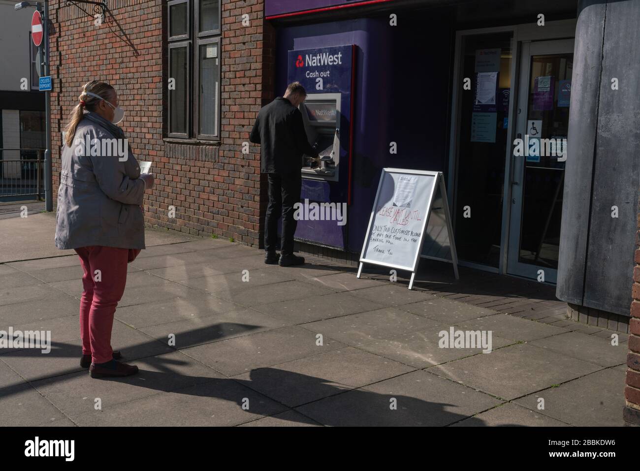 Una coda sul marciapiede al di fuori di una banca, osservando le misure di allontanamento sociale messe in atto durante il blocco del Regno Unito. Pandemia di coronavirus. Foto Stock