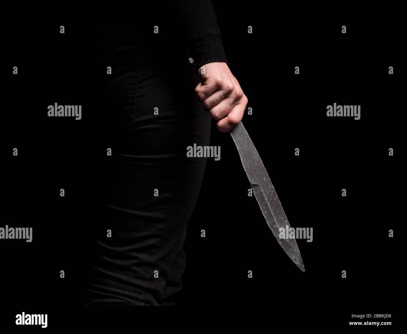 Ragazza che tiene in mano acciaio lancio coltello su sfondo nero Foto Stock