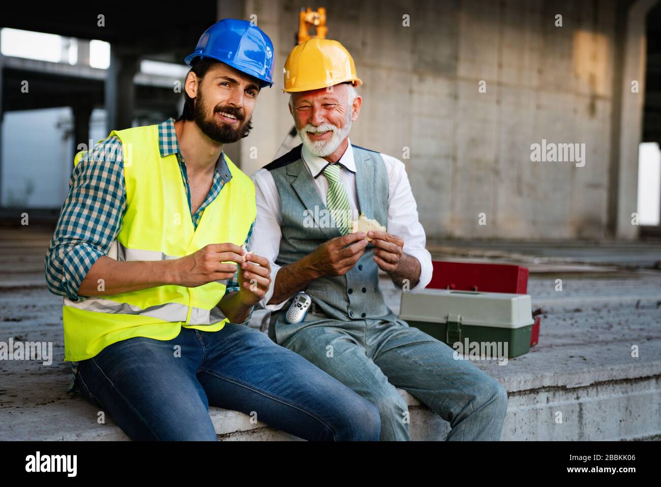 Felice maturo e giovane ingegnere, architetto, lavoratore seduto al sito di costruzione e di appoggio Foto Stock