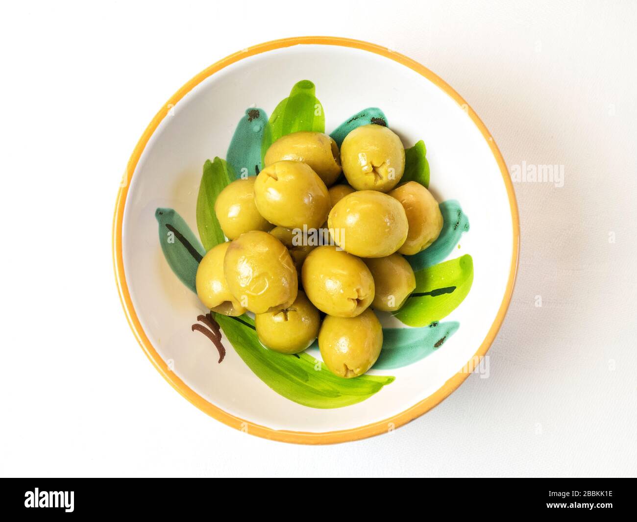 Una ciotola di olive verdi snocciolate su una tovaglia bianca Foto Stock