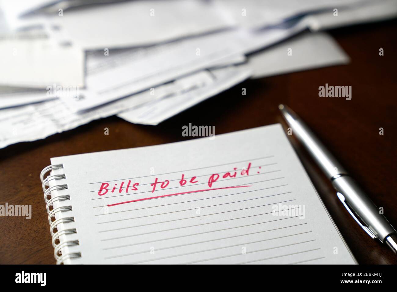 Fatture da pagare, scritte in rosso sul notebook con fatture e fatture in background. Concetto di disoccupazione o recessione. Foto Stock